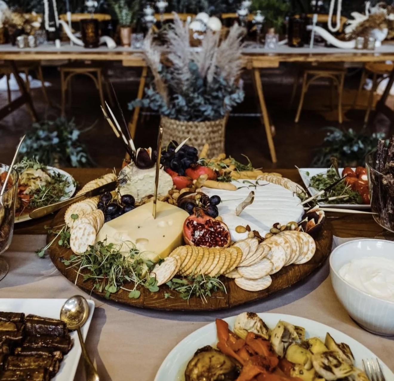 A generous cheese and fruit harvest table with crackers and vegetable platters