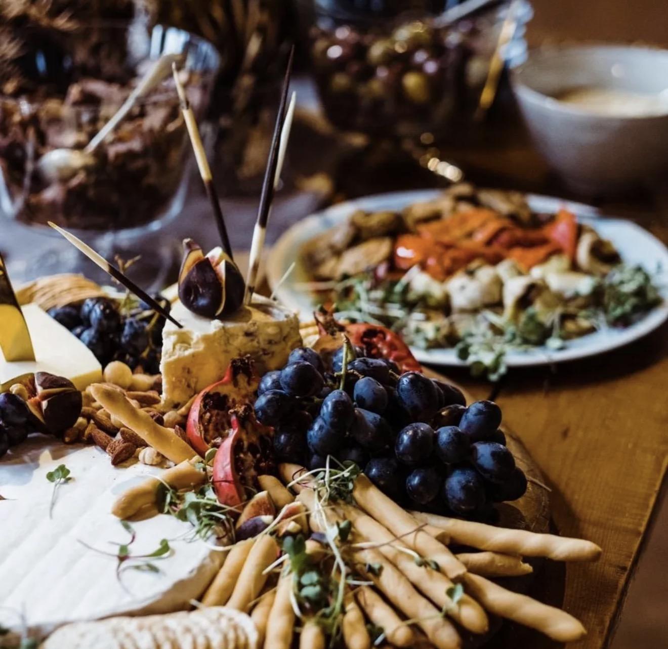 Cheeses, grapes, figs and breadsticks on a wooden harvest table