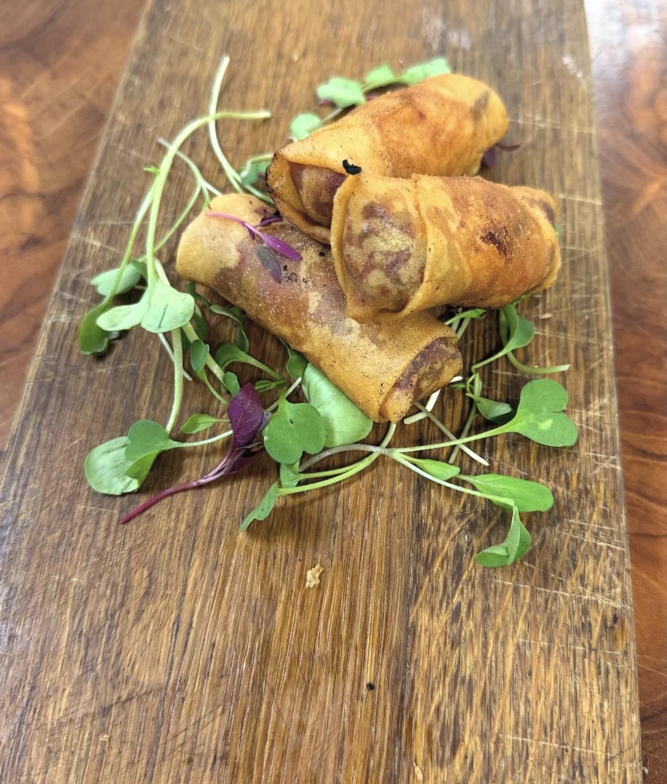 Golden canapé rolls with fresh microgreens on a wooden board