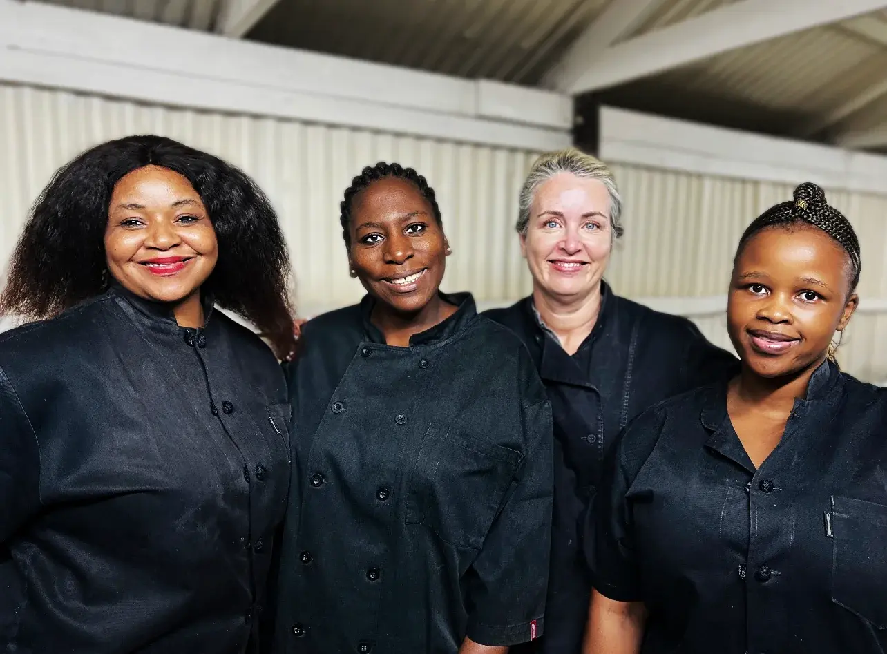 Four members of The Fat Aubergine kitchen team smiling together in black chef jackets