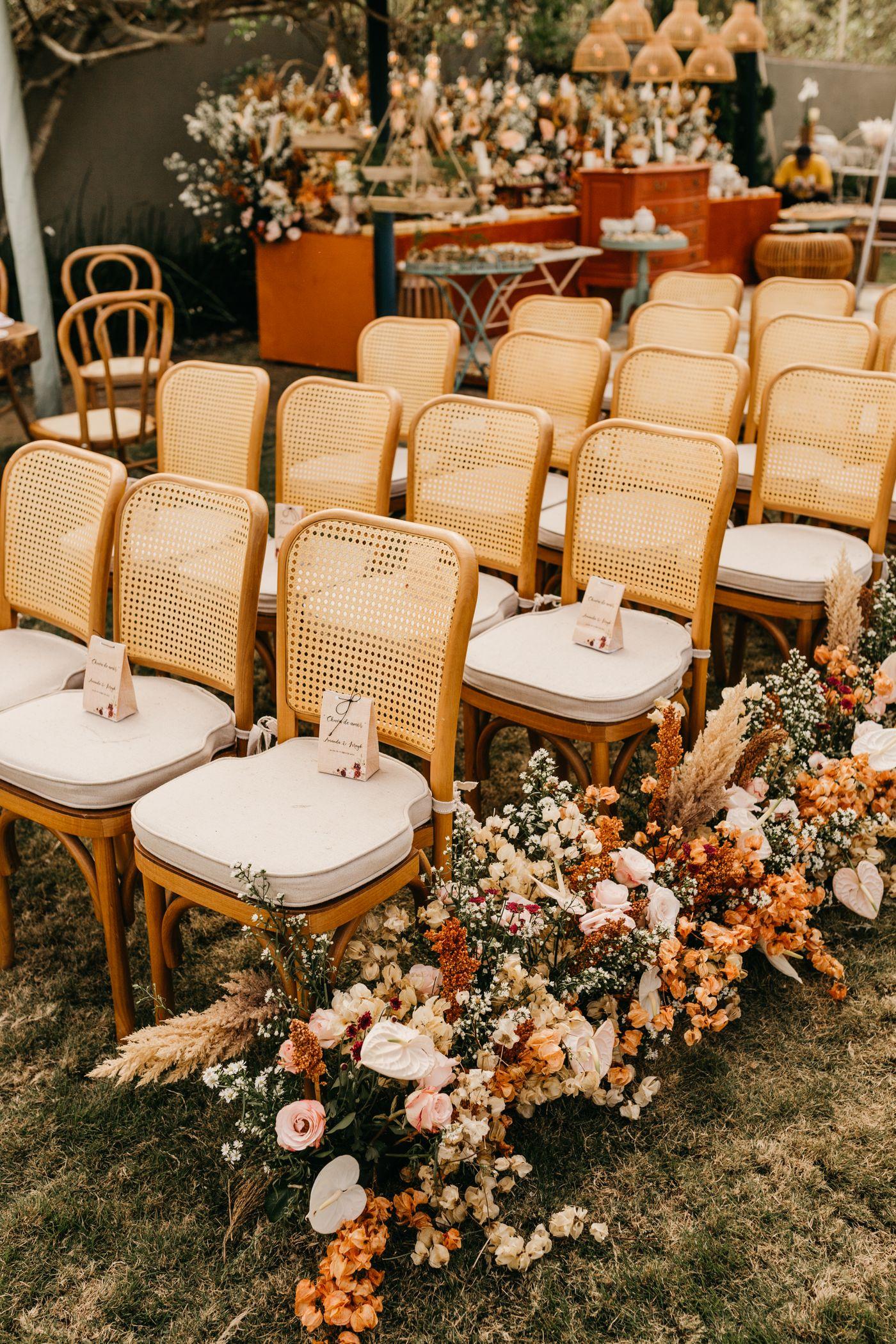 Wedding inspiration: an outdoor ceremony setting with woven chairs and warm floral arrangements (stock photograph)