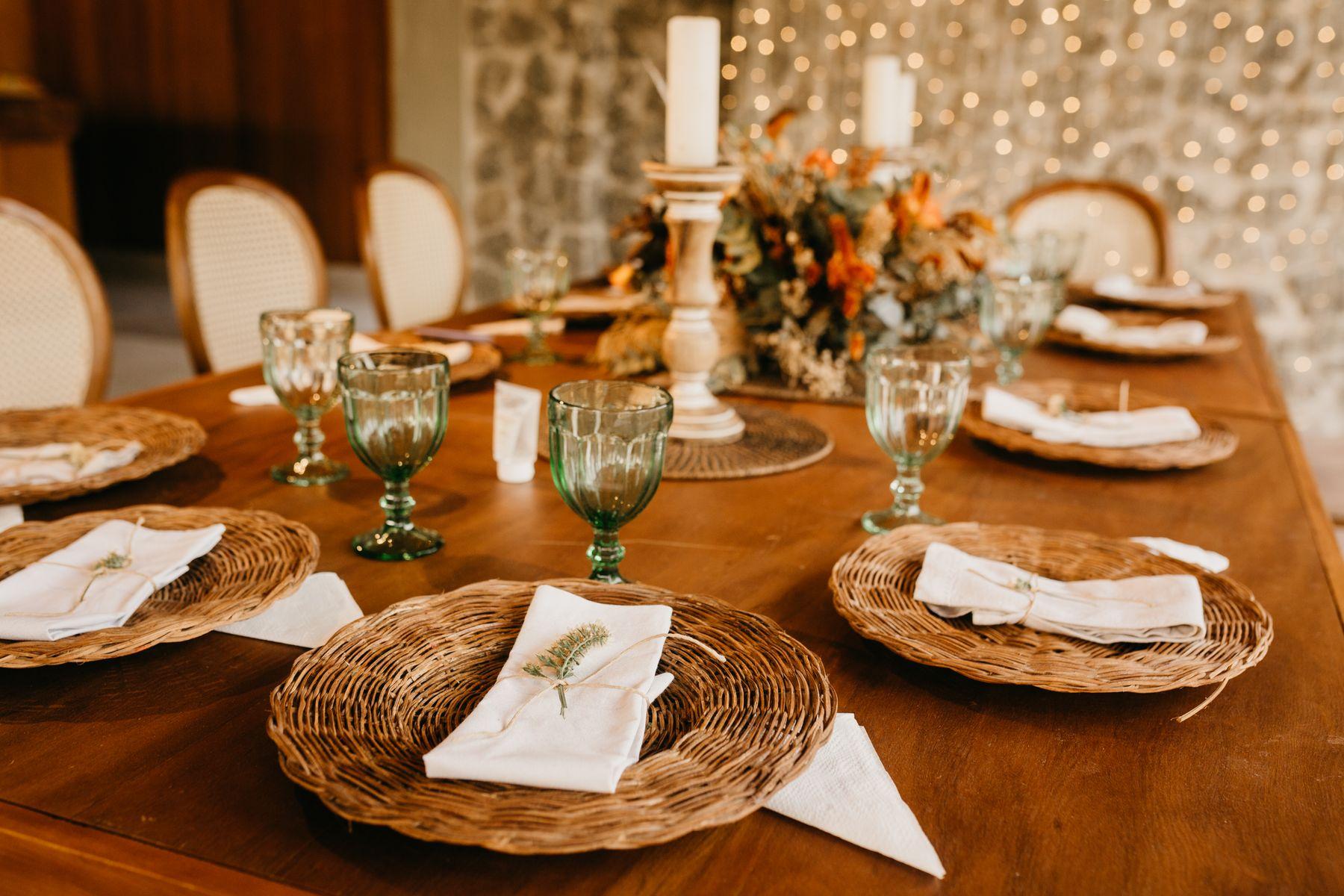 Wedding table inspiration: woven chargers, green glassware and flowers, stock photograph